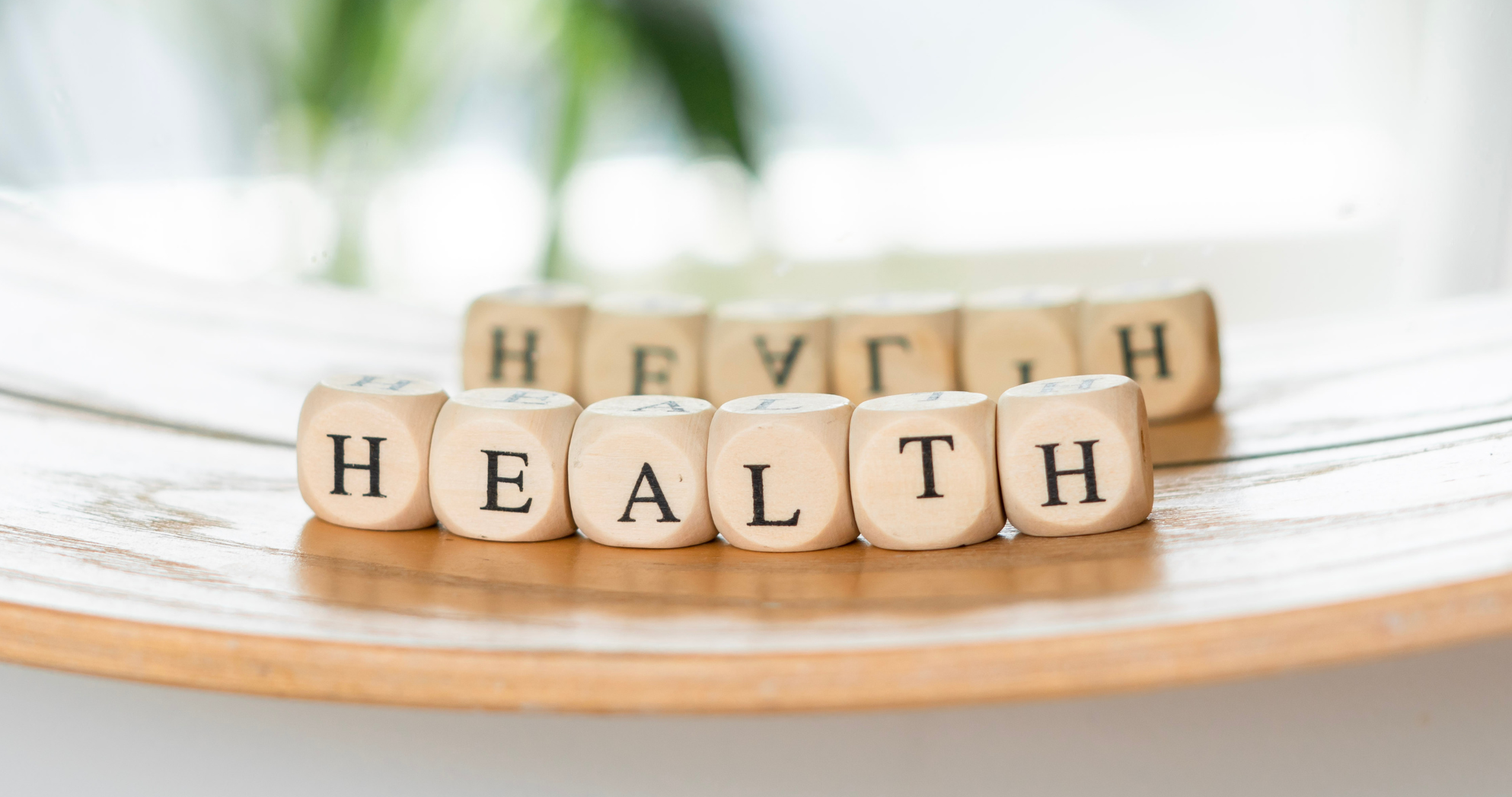 Wooden alphabet beads spelling “health” on a neutral background, symbolizing holistic wellness and quality of life through chiropractic care.