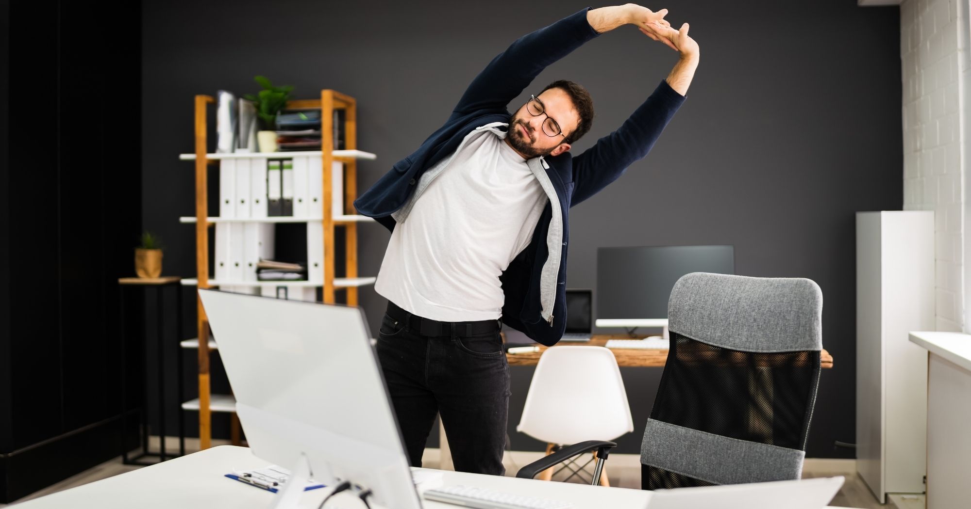 Man stretching at his desk in a crescent shape to relieve stiffness from sitting