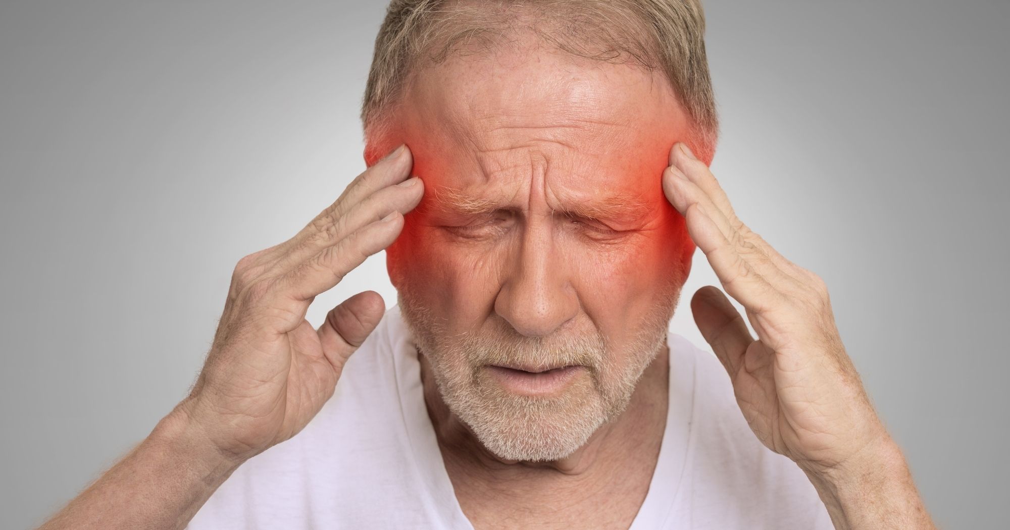 Middle-aged man holding his temples in pain from a headache, illustrating neck-related headache symptoms