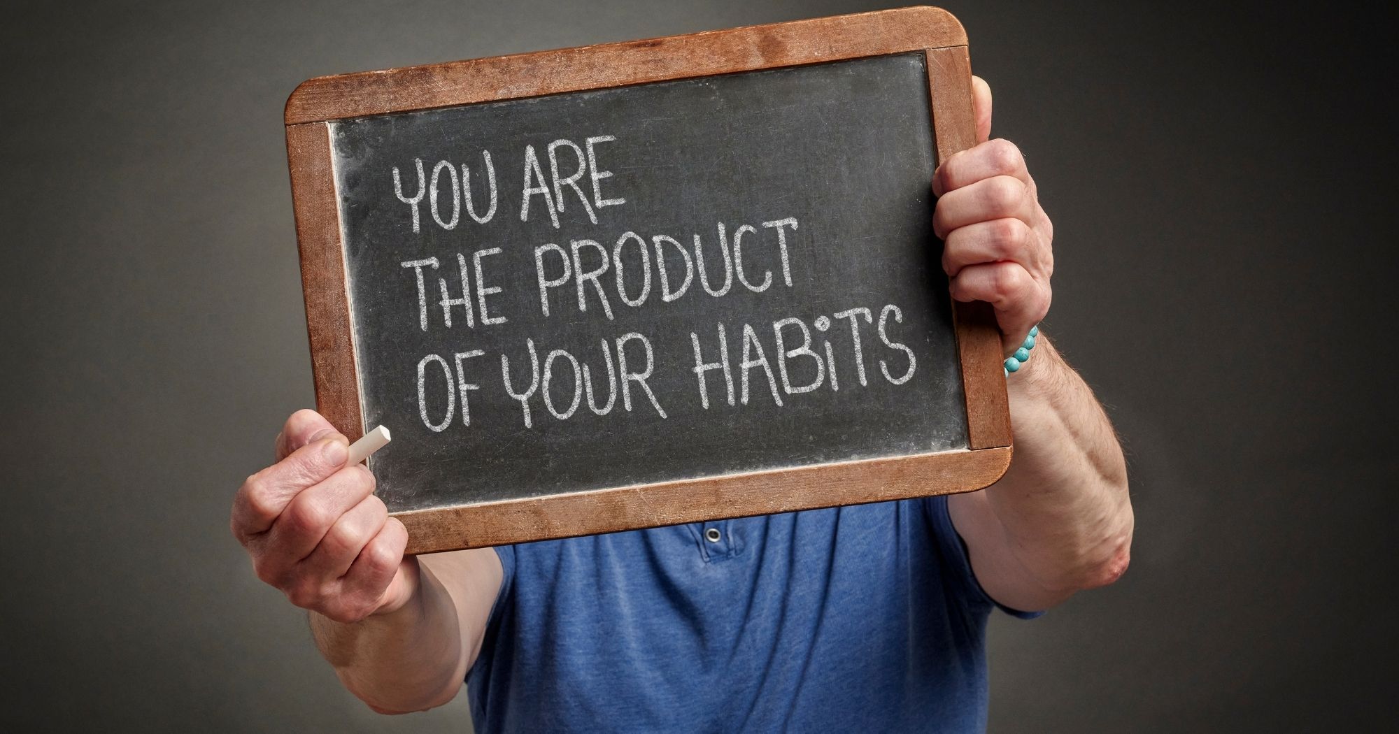 Person holding sign that says you are the product of your habits